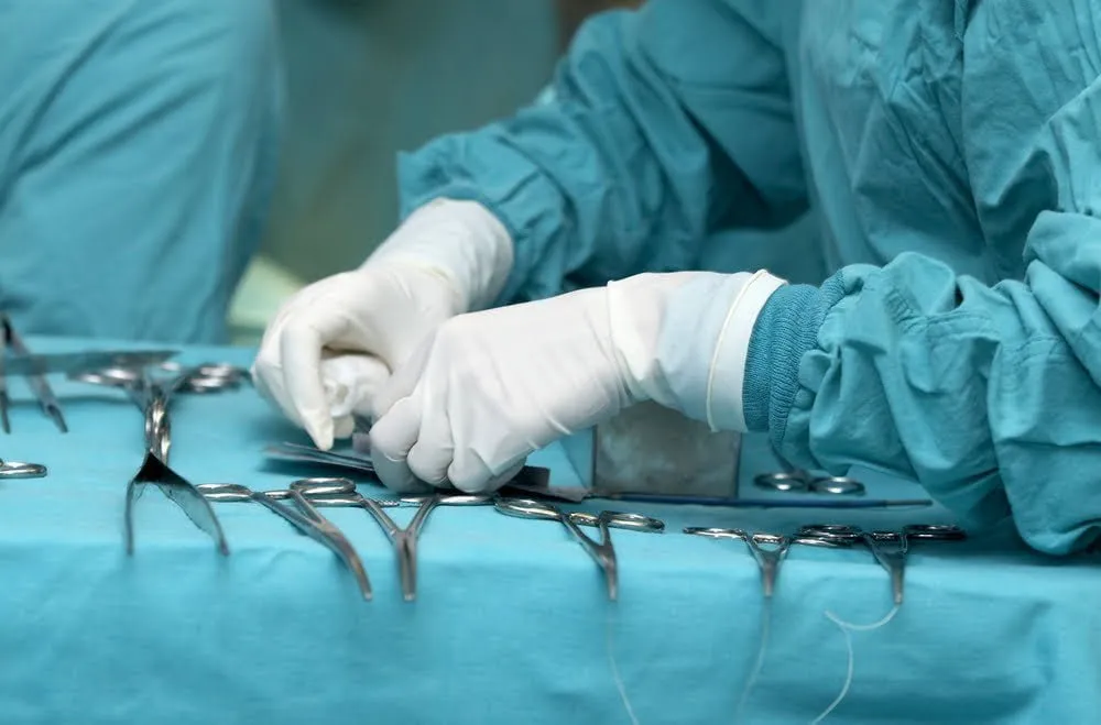 Surgery room with tools laid out and a surgeon in gloves.