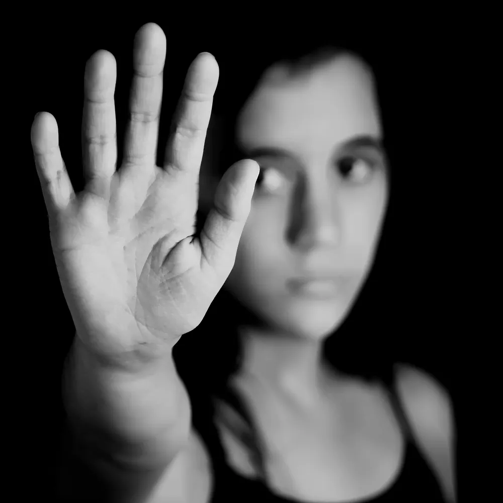 Woman in black and white with her hand up to the camera and a sad look on her face.