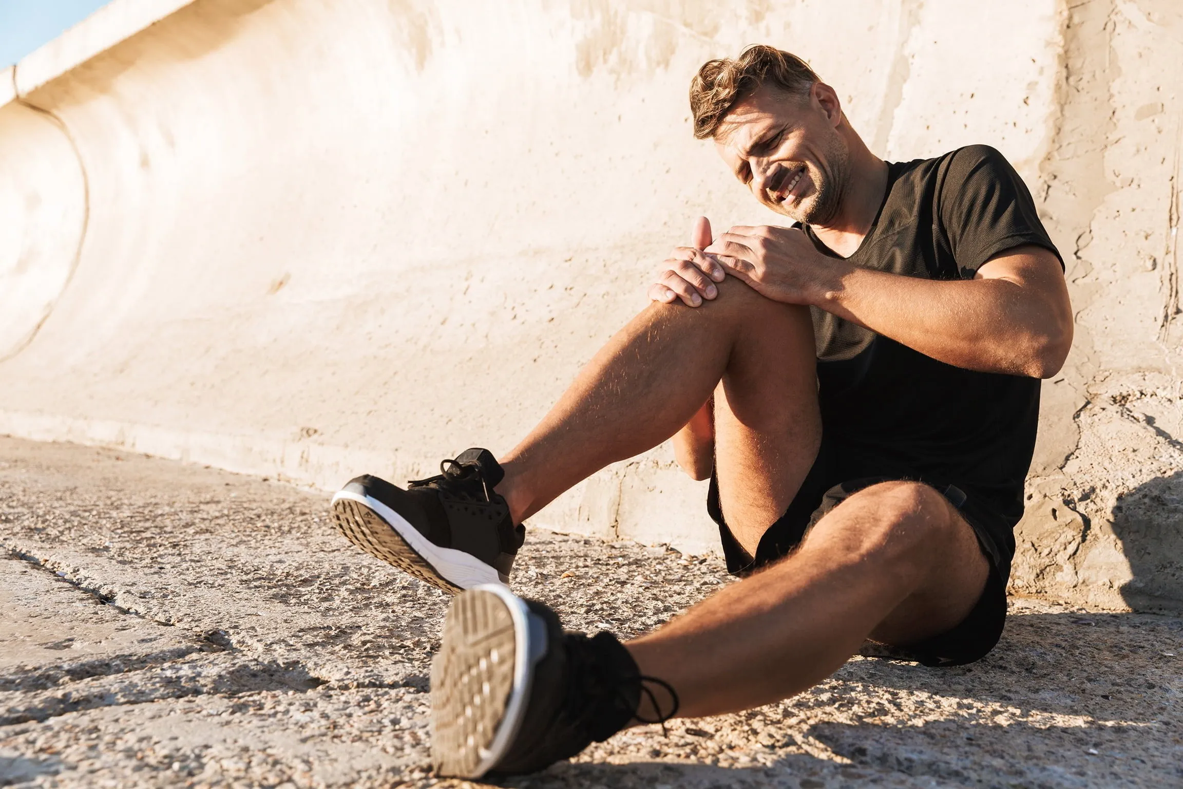 Male runner sitting on the ground holding knee in pain. If you’ve sustained an injury due to others’ negligence, our Idaho Falls personal injury attorneys can help you.
