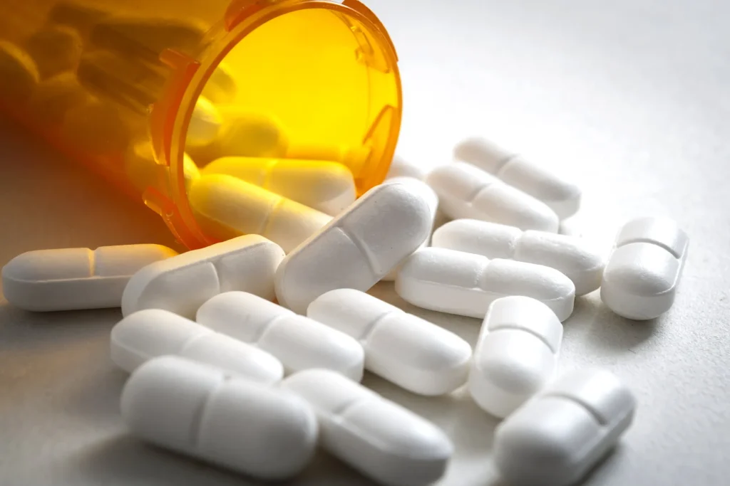 White prescription pills falling out of an orange pill bottle. If you have been injured due to a prescription drug, our team of defective drug lawyers is ready to fight for you.