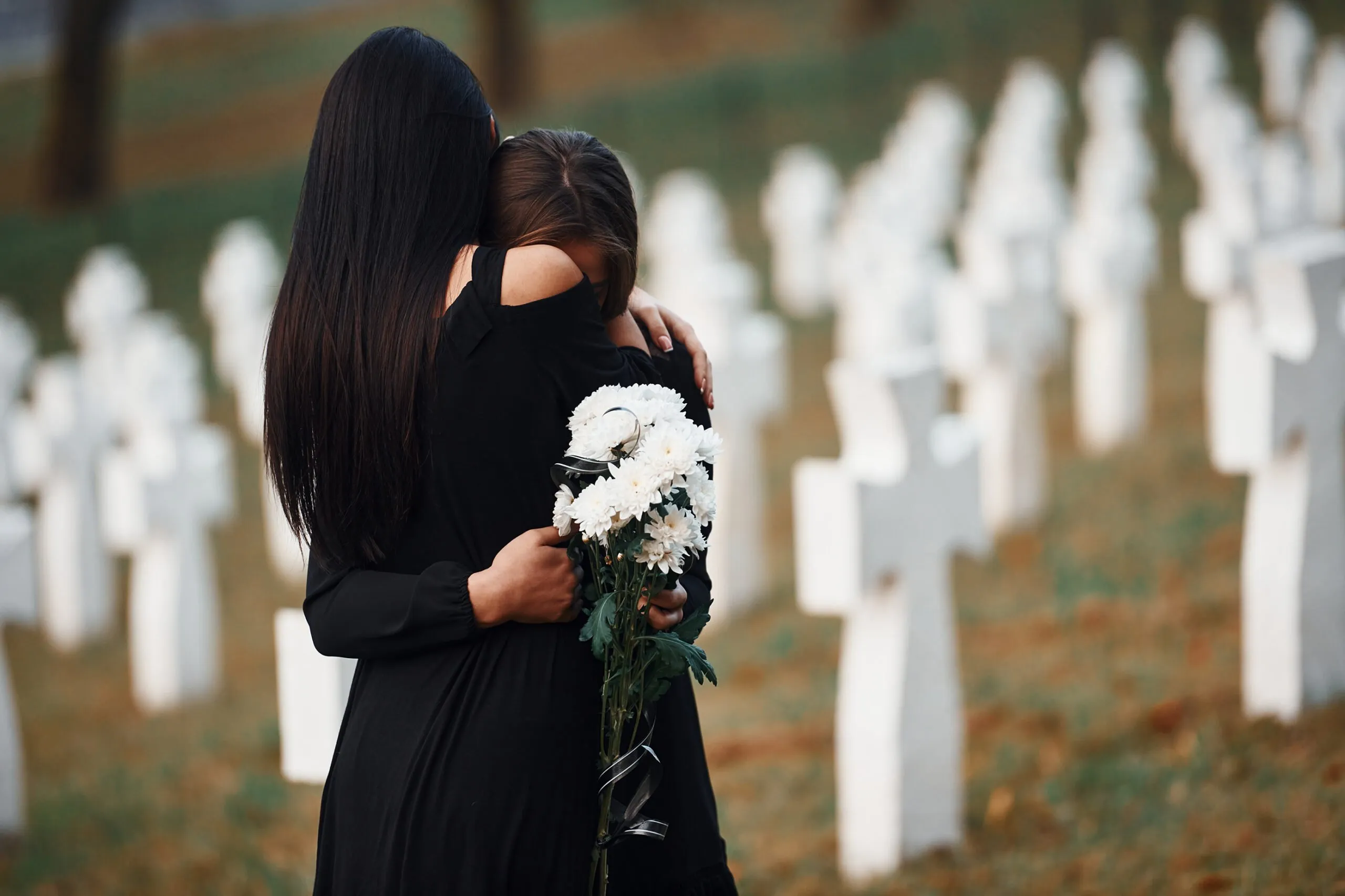 Two women hugging and crying at a cemetery. If you’ve lost a loved one due to the negligent acts of another, our Wyoming wrongful death lawyers can help you.
