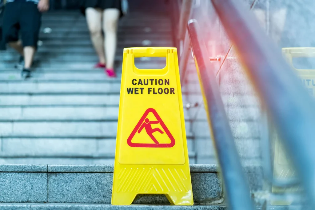 A caution wet floor sign on stairs to try to warn those passing by so they don't slip and injure themselves. If you slip or fall due to another's negligence, our personal injury lawyers in Gillette, WY can help.