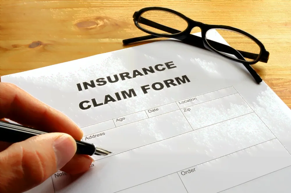Insurance claim form and glasses seen close up.