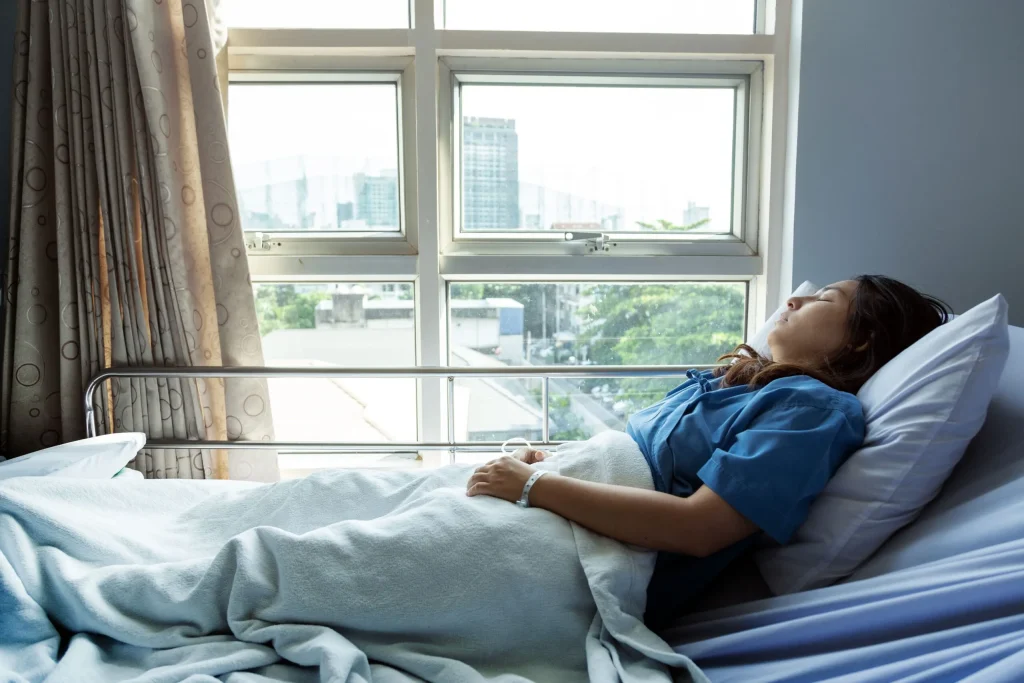 Woman lays in hospital bed with eyes closed. If you have a severe spinal cord injury due to someone else’s negligence or an accident, contact our Wyoming personal injury lawyer.