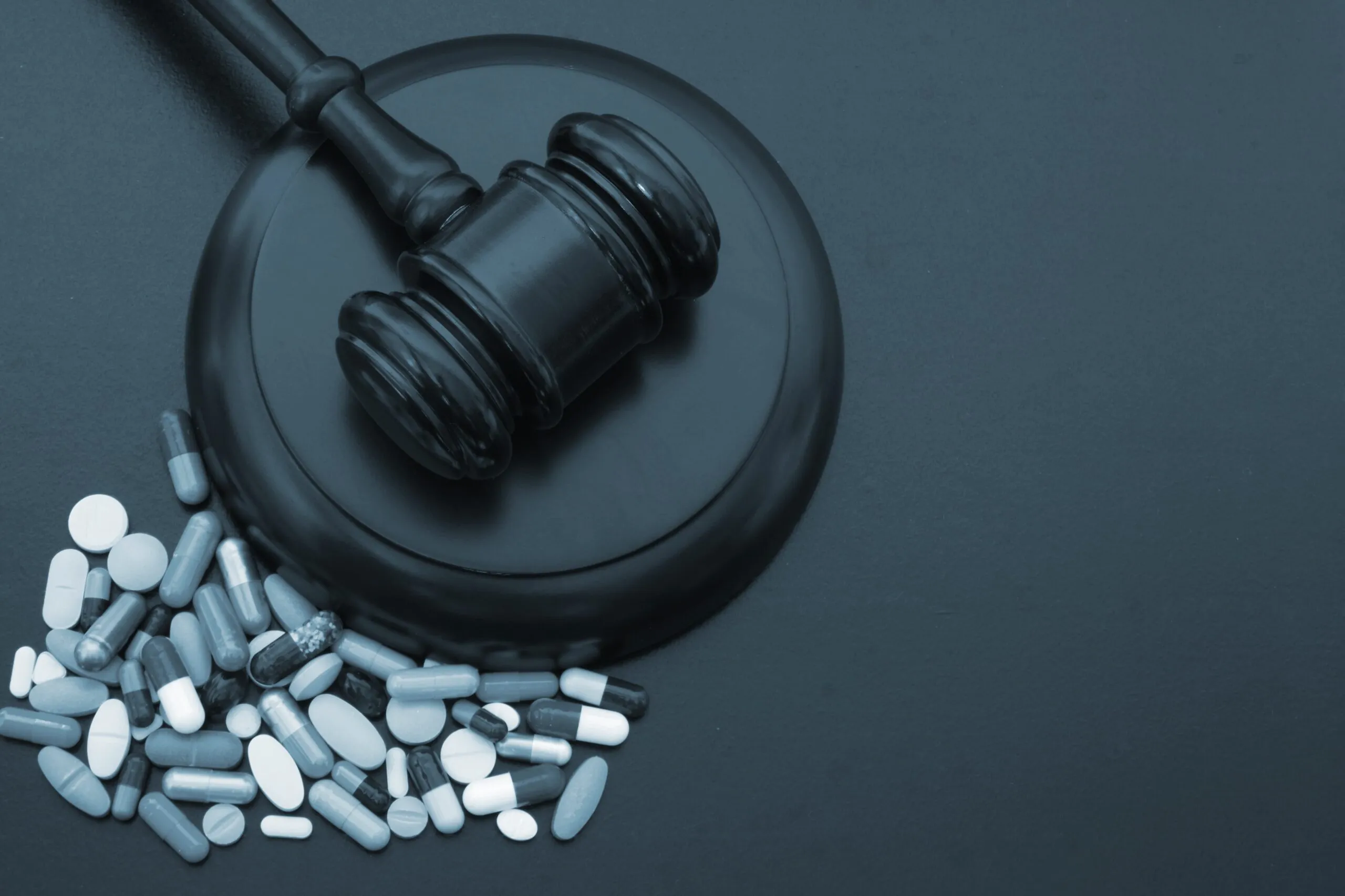 Wooden justice gavel sits on a table next to a pile of medical pills. If you are looking for justice after being injured by bad drugs or medical devices, contact our experienced pharmaceutical litigation attorneys in Wyoming.