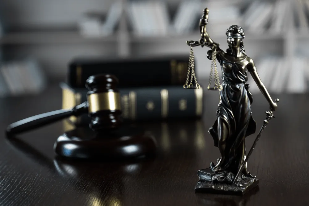 blind justice statue and a gavel next to some law books.