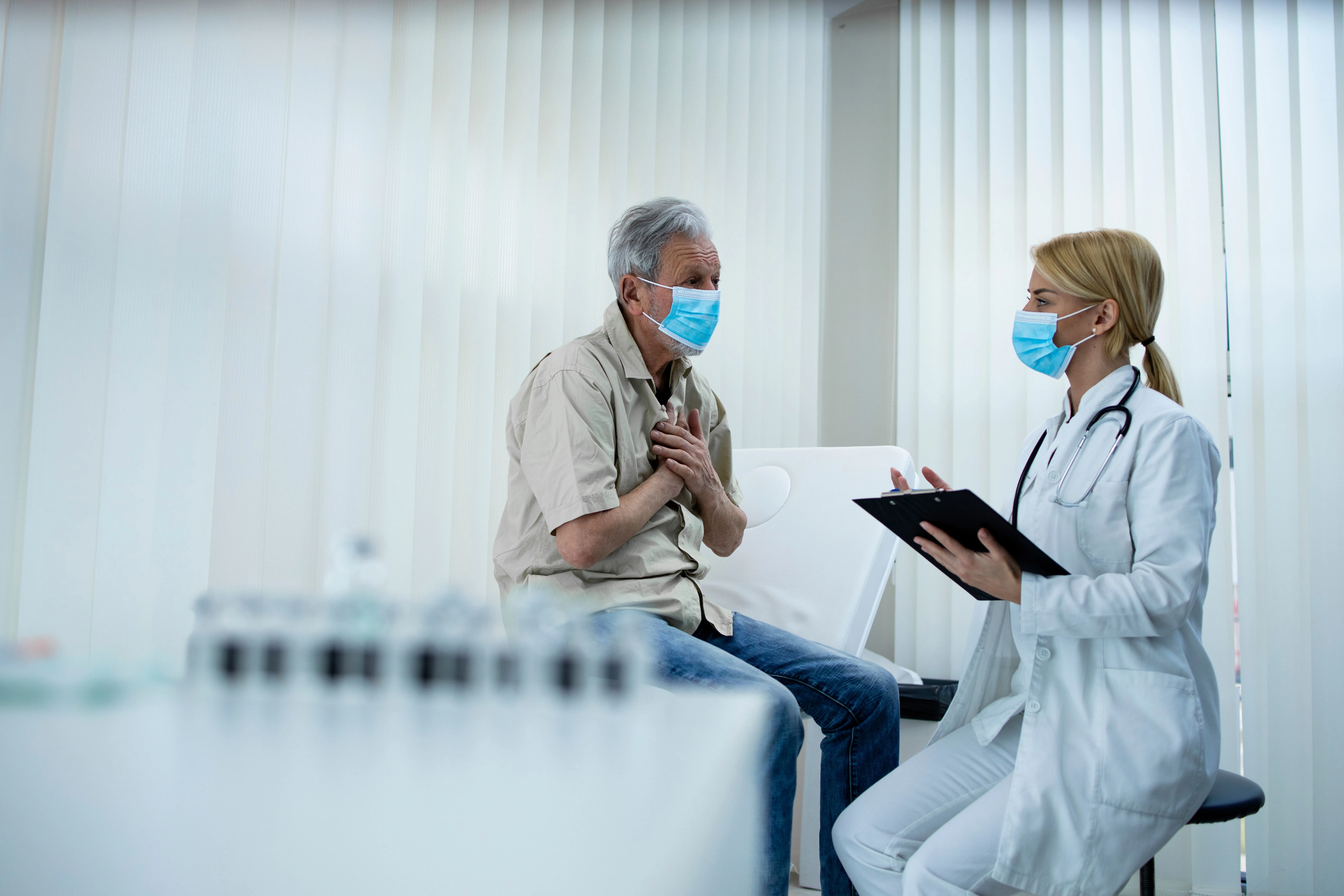 Man holds chest in discomfort during exam with doctor. For complex injuries from toxic exposure or catastrophic injuries, call our experienced injury lawyer in Wyoming today!