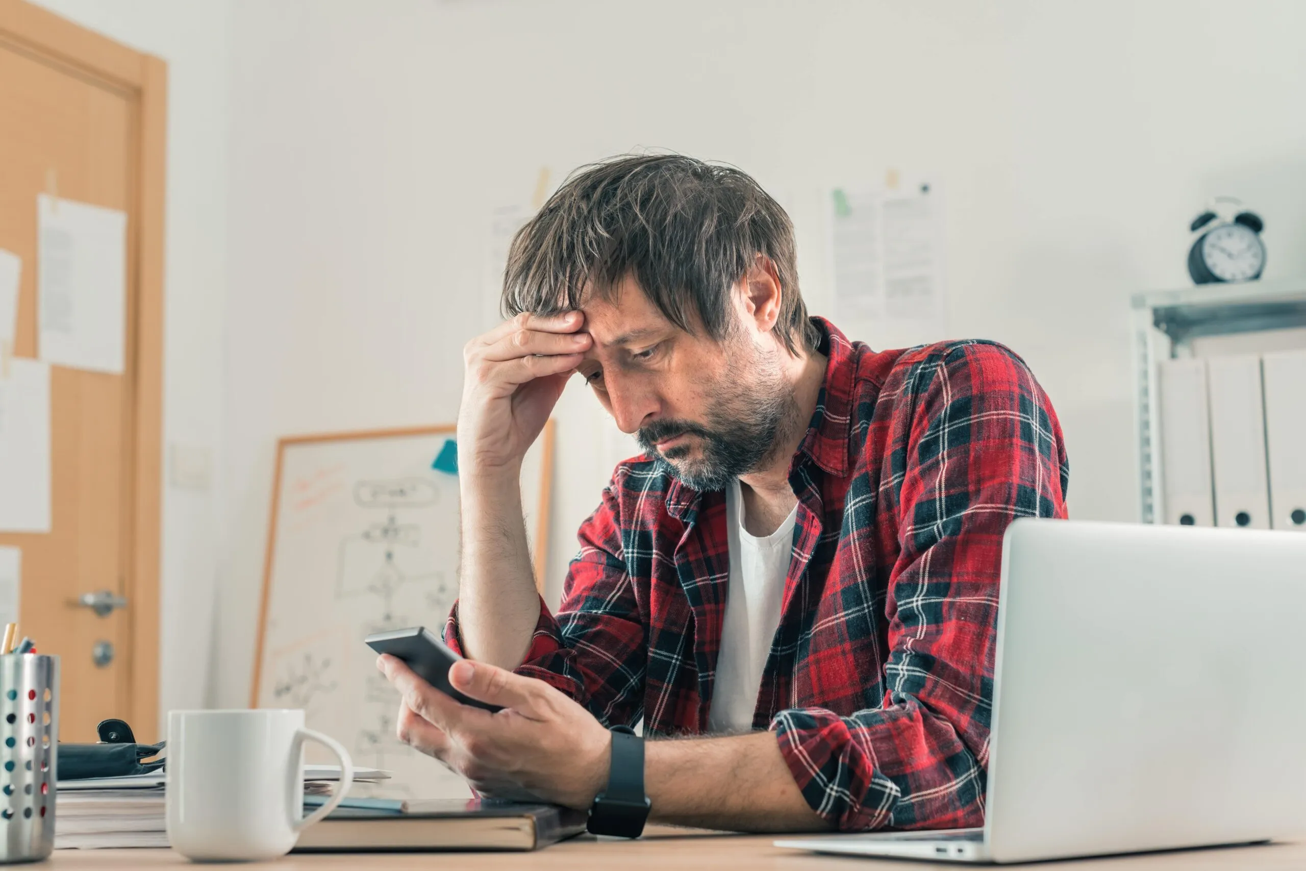 Man stares at his phone in frustration. Keep the companies accountable for their mistakes and contact a Wyoming consumer fraud lawyer if you’ve been a victim of a scam.