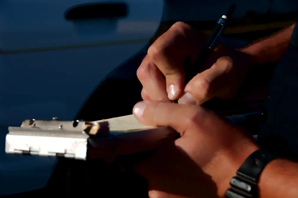 close up of a cop writing a ticket.